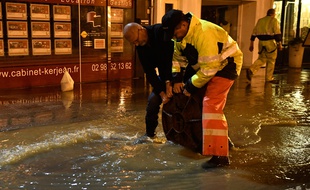 Des agents municipaux soulèvent une plaque d'égout dans une rue inondée à Morlaix, le 4 juin 2018.
