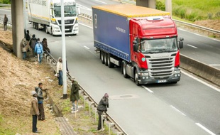 Des migrants, qui tentent d'accéder au tunnel sous La Manche, attendent sur le bord de l'autoroute A16 à Calais, le 23 juin 2015