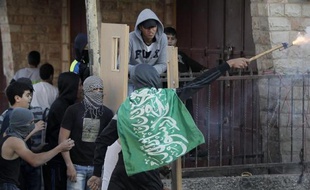 Des palestiniens utilisent des portes comme bouclier lors d'affrontements avec les forces de sécurité israéliennes dans le camps de réfugiés de Chouafat, le 6 novembre 2014