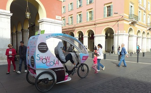 Carolina, conductrice d'un vélo-taxi, attend ses clients sur la place Massena de Nice.
