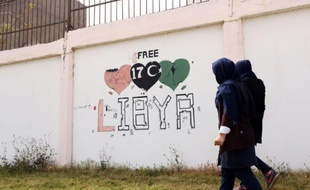 Des étudiants passent à côté d'un graffiti "Libye libre", à Tripoli, le 31 mars 2016