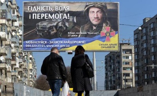 Des personnes marchent devant un panneau appelant les ukrainiens à rejoindre l'armée à Lviv le 17 mars 2015