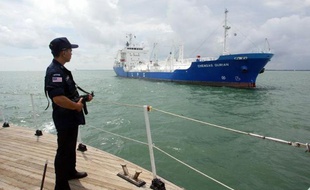 Un policier surveille le passage d'un tanker dans le détroit de Malacca, le 3 juillet 2003