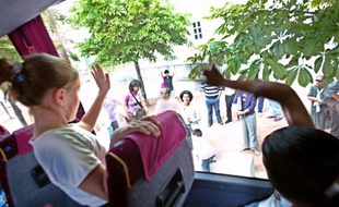 Des enfants font signe à leur parents par la vitre du bus qui les amènent en colonies de vacances