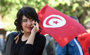 Une jeune femme tunisienne agite le drapeau national à Tunis.