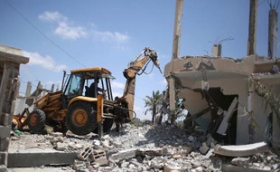 Des Palestiniens font des travaux pour enlever les ruines d'immeubles détruits lors de la guerre à Gaza en 2014, dans le village de Khuzaa, dans la Bande de Gaza, le 1er juin 2015