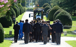 Employees of the Chateau Mouton Rothschild (in blue) and relatives walk next to the coffin carrying the body of baroness Philippine de Rothschild, pulled by a vineyard tractor, during her funeral ceremony on September 1, 2014 in Pauillac, western France. AFP PHOTO / JEAN-PIERRE MULLER