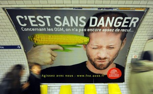 Des gens passent devant l'affiche d'une campagne contre les organismes génétiquement modifiés (OGM), le 15 février 2011, dans une station du métro parisien
