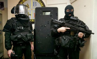 Des policiers de la BRI posent à côté d'un bouclier le 17 novembre 2015 à Paris sur lequel on voit les impacts de balles des terroristes, lors de l'intervention au Bataclan
