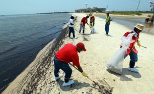 Des gens nettoient les plages de Waveland, dans le Mississippi, après la marée noire provoquée par l'explosion sur la plateforme pétrolière Deepwater Horizon exploitée par BP dans le golfe du Mexique le 9 juillet 2010