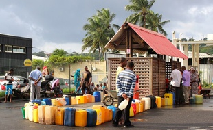 Des habitants de l'île remplissent des jerrycans d'essence, alors que les routes sont bloquées à Mayotte, le 7 mars 2018.
