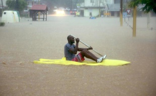 Un homme pagaie à travers l'eau des inondations qui ont secoué le village de Petit Bourg en Martinique, le 6 novembre 2015