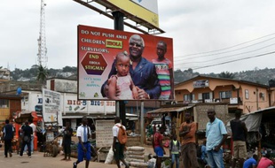 Des habitants de Freetown en Sierra Leone marchent sous une affiche de campagne contre Ebola représentant le président Ernest Bai Koroma