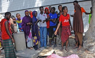 Des somaliens devant le corps d'une victime de l'explosion d'une voiture piégée devant un restaurant très fréquenté de Mogadiscio, le 21 avril 2015