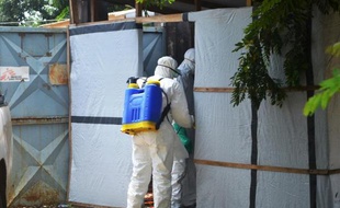 Des membres de la Croix Rouge préparent un corps à être enterré, dans la zone d'un hôpital de Conakry où les malades d'Ebola sont soignés, le 28 juin 2014