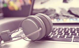 Illustration d'un casque audio devant un ordinateur.