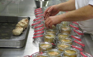 Illustration. Foies gras mis manuellement dans des pots en verre.