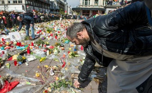 Un homme dépose des fleurs devant un mémorial improvisé place de la Bourse à Bruxelles lors de la marche pacifiste contre le terrorisme le 17 avril 2016