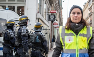 Les membres de l'Observatoire des pratiques policières portent des chasubles jaune et bleu lors des manifestations.