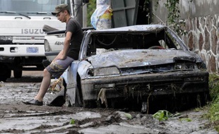 Un habitant du Salvador sur sa voiture détruite par les coulées de boue, le 8 novembre 2009.