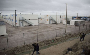 Des personnes migrantes passant devant les abris en conteneurs installés à Calais