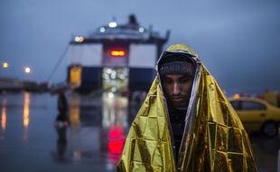 Un migrant enveloppé dans une couverture de survie attend d'embarquer à bord d'un ferry dans le port du Pirée, près d'Athènes, le 5 janvier 2016.