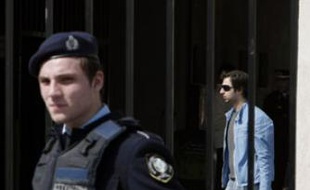 Un policier grec sécurise l'entrée de l'établissement athénien dans et devant lequel a eu lieu la fusillade.