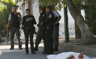 Des policiers fédérals méxicains enquêtent près du corps d'une femme assassinée avec son petit-ami à Ciudad Juarez le 5 juillet 2010.