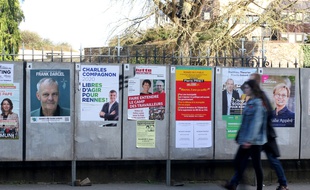 Des passants marchent devant les panneaux d'affichage des candidats aux élections municipales à Rennes, le 12 mars 2020.