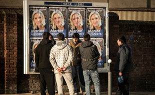 Des migrants regardent les panneaux électoraux à Calais avec en affiche la tête de liste FN de la région Nord, Marine Le Pen, le 7 décembre 2015