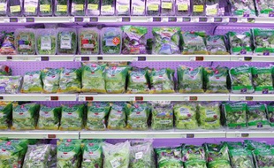 Des sachets de salade sur les rayons d'un supermarché.