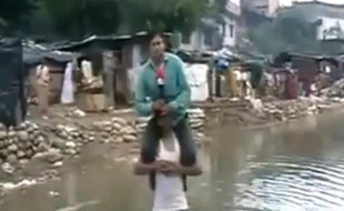 Un journaliste indien, qui faisait un reportage sur des inondations, apparait juché sur les épaules d'un rescapé