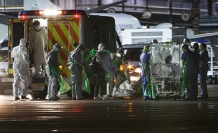 Une infirmière contaminée par le virus Ebola (c) en Sierra Leone descend d'une ambulance pour être placée dans un dispositif d'isolement sur le tarmac de l'aéroport de Glasgow avant d'être transportée par avion vers l'hôpital Royal Free de Londres, le 30 décembre 2014