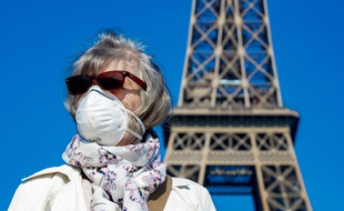 Une femme porte un masque devant la Tour Eiffel, à Paris le 12 avril 2020.