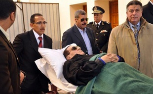 Ousted Egyptian President Hosni Mubarak is wheeled on a stretcher out of the police academy after his murder trial in Cairo on January 10, 2012. AFP PHOTO / STR