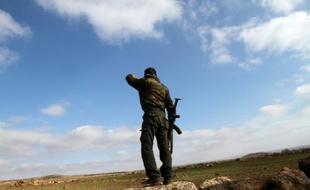 Un soldat syrien regarde en direction de la ville de Daraa depuis sa position à Soueida, dans le sud de la Syrie, le 23 janvier 2013