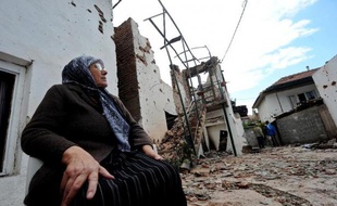 Une femme est assise à l'extérieur de sa maison en ruine, le 11 mai 2015 à Kumanovo, dans le nord de la Macédoine