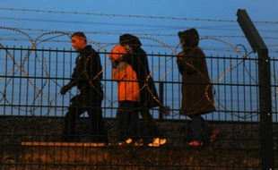 Des policiers arrêtent des migrants sur le site de Eurotunnel à la gare de Calais, le 13 août 2015