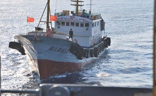 Un marin chinois utilise un long crochet pour tenter de s'accrocher à un câble déployé par un navire américain en mer de Chine méridionale