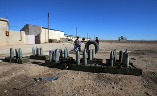 Des enfants syriens jouent avec un pneu près d'un canon à Sadad le 14 novembre 2015