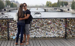 Un couple s'embrasse sur le pont des Arts à Paris, recouvert de "cadenas d'amour", en août 2013