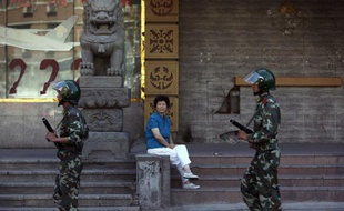 Une femme regarde passer des soldats de l'armée chinoise dans une rue de Urumqi, le 9 juillet 2009.