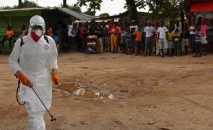Un agent santiaire, en combinaison de protection, procède à une opération de désinfection dans un quartier de Monrovia où une personne est décédée du virus Ebola, le 10 septembre 2014 au Liberia