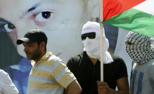 Un homme porte le drapeau palestinien derrière une photo géante de Mohammed Abu Khdeir, lors des funérailles de ce jeune palestinien, le 4 juillet 2014 à Jérusalem