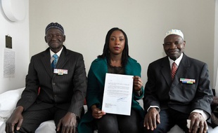 Ousmane Sagna (G) et Guorgui M' Bodji (D), deux anciens tirailleurs sénégalais, posent aux côtés d'Aïssata Seck (C), qui tient une lettre de François Hollande, le 22 décembre 2016, à Bondy, près de Paris.