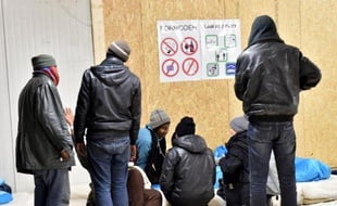Des migrants conversent avant de passer la nuit dans un hangar aménagé et chauffé dans le cadre du déclenchement du niveau 2 du plan grand froid, le 27 décembre 2014 à Calais