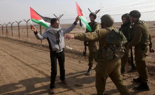 Des soldats israéliens empêchent un homme de mettre des drapeaux palestiniens sur le grillage marquant la frontière entre Israël et la Jordanie, le 1er janvier 2014
