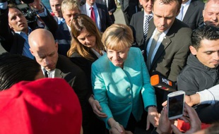 Angela Merkel serre la main de réfugiés alors qu'elle visite un centre d'enregistrement de demandes d'asile, le 10 septembre 2015 à Berlin
