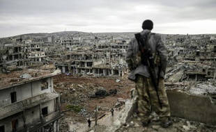 Un tireur kurde, regarde la ville détruite de Kobané en Syrie, reprise de l'Etat Islamique, le 30 janvier 2015