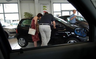 Un couple regarde l'intérieur d'une automobile chez un concessionnaire Renault.